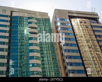 Zwei moderne Hochhäuser mit reflektierenden Glasfassaden im Sonnenlicht, moderne Hochhäuser mit Glasfassaden und vielen Fenstern, Abu dhab Stockfoto