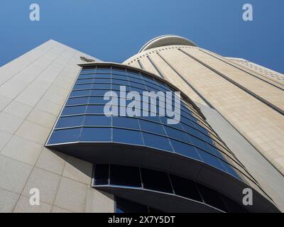 Moderne Gebäude mit Glasfenstern, die sich gegen den klaren blauen Himmel erheben, von unten fotografiert, moderne Wolkenkratzer mit Glasfassaden und vielen Fenstern Stockfoto