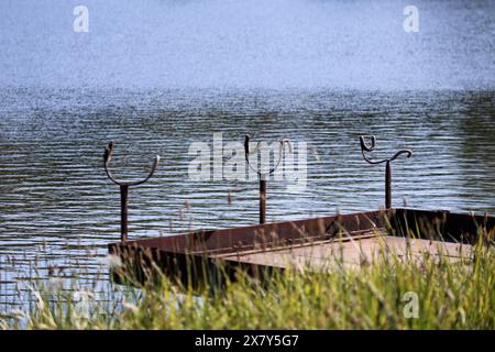 Pier fpr Angeln und steht für Angelruten am Ufer des Teichs Stockfoto