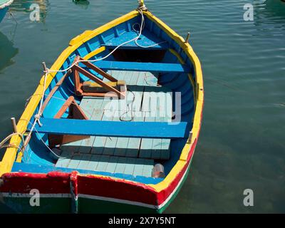 Ein farbenfroher Holzboot liegt ruhig auf dem Wasser im Hafen, viele farbenfrohe Fischerboote in einem Hafen im Mittelmeer, Marsaxlokk, malta Stockfoto