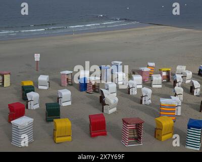 Mehrere bunte Liegestühle sind am Sandstrand unter bewölktem Himmel verteilt, Liegestühle und Strandzelte am Meer unter bewölktem Himmel, Board Stockfoto