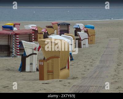Mehrere Liegestühle stehen am Sandstrand eines ruhigen Strandes mit bewölktem Himmel, Liegestühle und Strandzelte am Meer mit bewölktem Himmel, Promenade Stockfoto