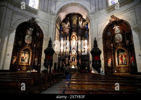 Iglesia San Nicolas de Bari, Altar in einer barocken Kirche mit Menschen in den Bänken, verzierte Holzdekorationen und prächtige Architektur, Old To Stockfoto