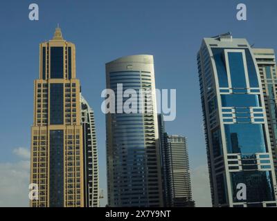 Drei verschiedene Wolkenkratzer mit modernen Glasfassaden stehen nebeneinander unter klarem Himmel, beeindruckender Skyline einer modernen Stadt mit spektakulärem Himmel Stockfoto