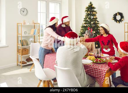 Fröhliche große Familie, die beim Weihnachtsessen Wein serviert Stockfoto