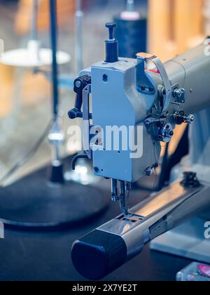 Nahaufnahme einer robusten, industriellen Nähmaschine auf einem Arbeitstisch mit komplexen Komponenten und mechanischem Design. Stockfoto