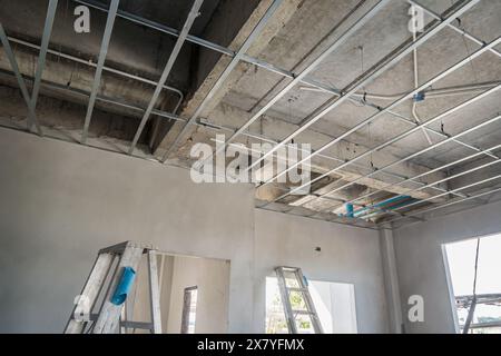 Installation eines Metallrahmens für die Gipskartondecke im Gebäude im Bau Stockfoto