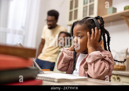 Afroamerikanisches Kind, das am Tisch sitzt und mit Hilfe ihres digitalen Tablets ihre Schularbeit beendet Stockfoto
