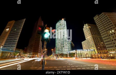 Nächtliches Foto einer geschäftigen Kreuzung am Potsdamer Platz mit Fahrzeugwegen und einer Ampel. Pulsierende Stadtlandschaft an einer rastlosen Kreuzung. Berlin Stockfoto