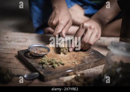 Ein Mann bereitet Marihuana auf einem Schneidebrett zu rauchen, Person, die Drogen raucht, Drogensüchtig, Drogensucht und Entzugssymptome Konzept. DrugsInte Stockfoto