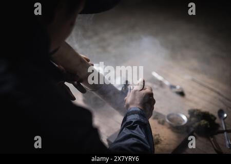 Ein Mann bereitet Marihuana auf einem Schneidebrett zu rauchen, Person, die Drogen raucht, Drogensüchtig, Drogensucht und Entzugssymptome Konzept. DrugsInte Stockfoto