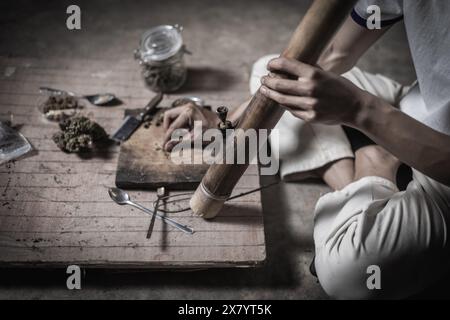 Ein Mann bereitet Marihuana auf einem Schneidebrett zu rauchen, Person, die Drogen raucht, Drogensüchtig, Drogensucht und Entzugssymptome Konzept. DrugsInte Stockfoto