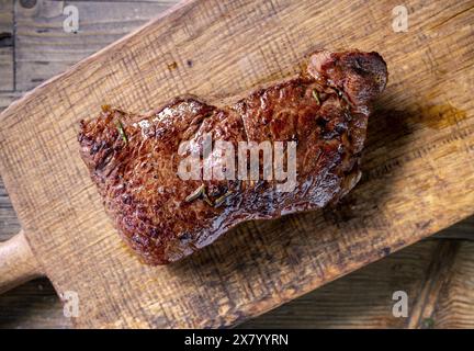 Frisches gegrilltes Rindfleischsteak mit Salz und Pfeffer auf hölzernem Schneidebrett, Blick von oben Stockfoto