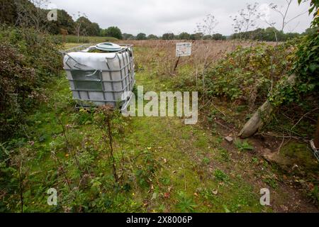 Ein großer Plastiktank, der auf einem unbewohnten und bewachsenen Feld zwischen Manningtree und Bradfield in Essex steht, vielleicht eine große Fliege, die umkippt? Stockfoto