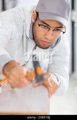 Handwerker, der mit Hammer auf der Planke arbeitet Stockfoto