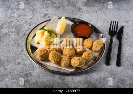 Gebratene Muscheln auf einem Metallteller mit Kartoffelsalat auf der Seite. Türkischer Name: Midye Tava Stockfoto