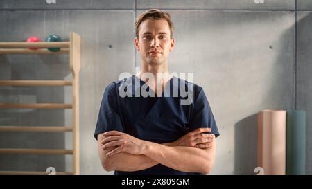 Porträt einer gutaussehenden professionellen männlichen Krankenschwester, die für die Kamera steht und posiert, lächelnd im medizinischen Rehabilitationszentrum. Physiotherapie-Assistent Im Krankenhaus. Junger Praxisarzt. Stockfoto