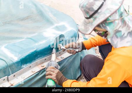 Arbeiter verwenden Heißkeilgebläse aus Kunststoff-Leinwand und rostfreie Rollkompresse auf der Kalotte der Abwasserbehandlung. Stockfoto