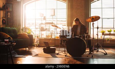 Junge Frauen spielen Schlagzeug während einer Bandprobe in einem Loft Studio bei warmem Sonnenlicht am Tag. Drummer Girl, das vor einem Live-Konzert auf der Bühne mit anderen Musikern praktiziert. Stockfoto