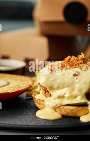 Offener Burger mit Käse-Sauce und knusprigen gebratenen Zwiebeln Stockfoto