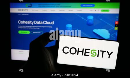 Person mit Smartphone und Logo des US-Datenverwaltungsunternehmens Cohesity Inc. Vor der Website. Schwerpunkt auf dem Display des Telefons. Stockfoto