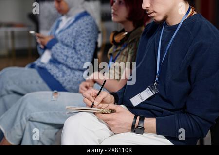 Selektive Fokusaufnahme eines jungen Mannes aus dem Nahen Osten, der Notizen in Notizbuch auf einer Konferenz an der Universität schreibt Stockfoto