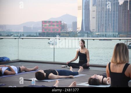 Yogalehrerin und ihre Schüler machen Meditation im Freien an der Wan Chai Promenade in Hongkong, China Stockfoto