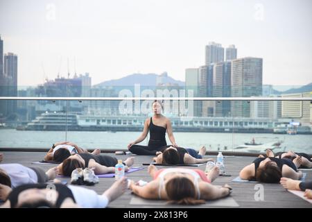 Yogalehrerin und ihre Schüler machen Meditation im Freien an der Wan Chai Promenade in Hongkong, China Stockfoto