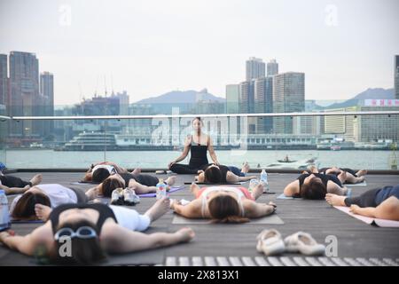 Yogalehrerin und ihre Schüler machen Meditation im Freien an der Wan Chai Promenade in Hongkong, China Stockfoto