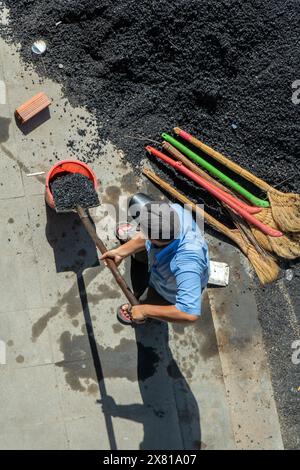 Ein Arbeiter mit einer Schaufel lädt Baumaterial in einen Eimer Stockfoto