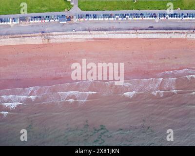 Luftbild einer langen Reihe von Strandhütten an einem Sandstrand, während die Wellen ins Ufer Rollen Stockfoto