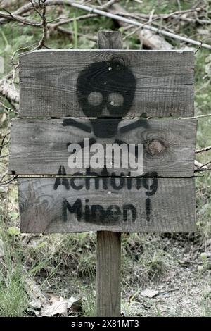 Holzschild mit der Aufschrift „Achtung Minen“. Seien Sie vorsichtig, Minen. Stockfoto