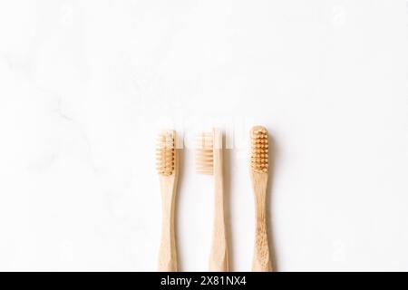 Drei umweltfreundliche Bambuszahnbürsten auf weißem Hintergrund. Natürliches Bio-Badezimmerkonzept. Flach, Draufsicht, Kopierraum Stockfoto