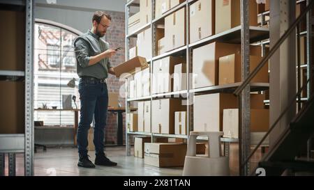 Warehouse Inventory Manager scannt mit dem Smartphone einen Barcode auf dem Paket und bereitet einen kleinen Karton für das Porto vor. Schwarzer, multiethnischer Eigentümer eines kleinen Unternehmens, der im Lager arbeitet. Stockfoto