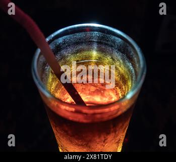 Nächtliche Nahaufnahme eines erfrischenden, gekühlten Cocktails mit Stroh in der schwach beleuchteten Bar Stockfoto