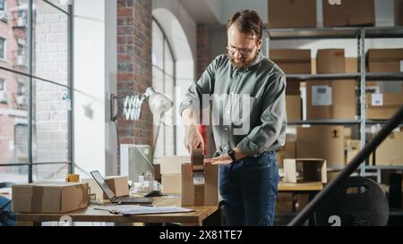Stilvoller Lagerarbeiter, der ein kleines Paket für den Versand vorbereitet. Inventory Manager kleben einen Karton vor dem Versand an den Kunden mit Klebeband. Eigentümer eines kleinen Unternehmens, der in der Lagereinrichtung arbeitet. Stockfoto