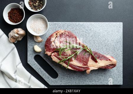 Frisches rohes Rindfleisch-Steak mit Salz auf Steinschneidebrett, Draufsicht Stockfoto