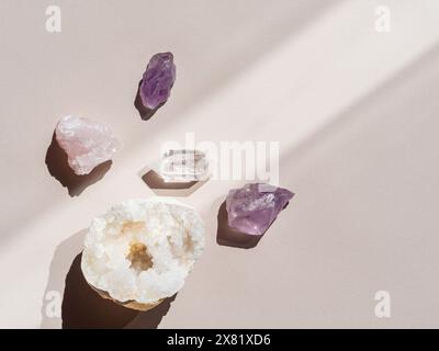 Sammlung von Kristallen Quarz und Amethyst auf beigefarbenem Hintergrund mit Schatten des Sonnenlichts. Draufsicht. Kopierbereich Stockfoto