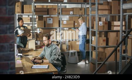 Aufnahme eines multikulturellen Teams von Lagerarbeitern bei der Arbeit im Lager des Internet Shops. Eigentümer kleiner Unternehmen und Lagerbestandsmanager, die an Notebooks, Tablets und Paketen für die Lieferung arbeiten. Stockfoto