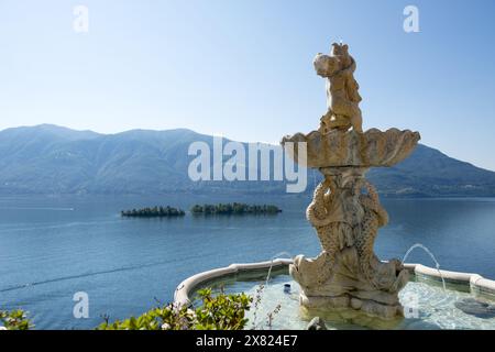 Brunnenstatue mit Blick auf den Lago Maggiore mit Brissago-Inseln und Berg an einem sonnigen Tag in Ronco sopra Ascona, Tessin, Schweiz. Stockfoto