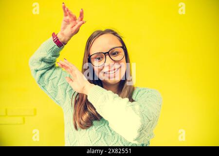 Eine Frau mit Brille und grünem Pullover. Sie tanzt energisch, mit erhobenen Händen und einem fröhlichen Gesichtsausdruck Stockfoto