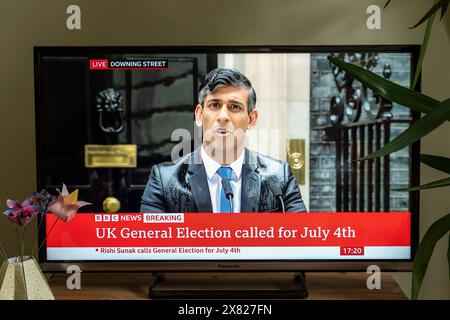 Der britische Premierminister Rishi Sunak kündigt die Parlamentswahlen für den 4. Juli 2024 in den BBC TV News an, da er von Regen durchnässt wird. Downing Street, London. Stockfoto