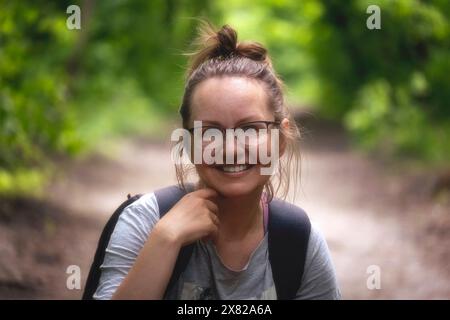 Nahaufnahme eines Porträt einer Europäerin mit Brille in lässiger Kleidung ohne Make-up auf einem Morgenspaziergang in einem Park oder Wald im Sommer oder Frühling Stockfoto