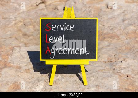Symbol für SLA Service Level Agreement. Konzeptworte SLA Service Level Agreement auf schöner gelber Tafel. Wunderschöner Steinhintergrund. Geschäfts-SLA Stockfoto