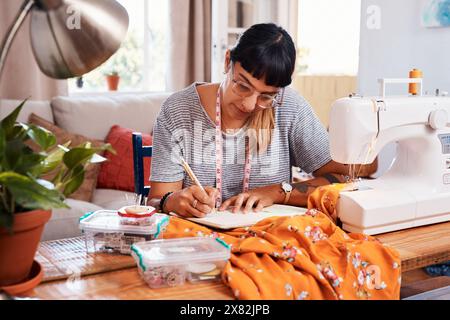 Schreiben, Notizen und Modedesignerin im Heimstudio für Style mit Maßband für Beruf. Schneiderei, Nähmaschine und Schneidtisch Stockfoto