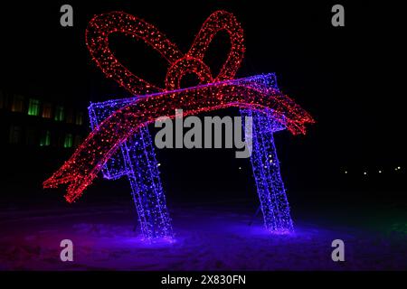 Weihnachtsneon-Geschenkfigur in blau und rot. Außendekoration. Stockfoto