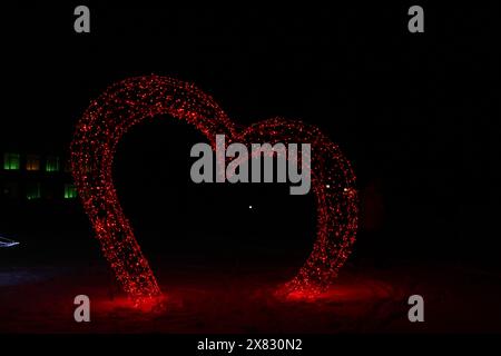 Weihnachtsfigur Beleuchtung Rotes Herz bei Nacht. Festliche Atmosphäre Neon-Fotozone. Stockfoto