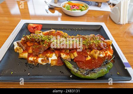Türkischer Kebab mit Pistazien, serviert mit aufgeschnittenem Fladenbrot, Joghurt und Tomatensauce. Stockfoto