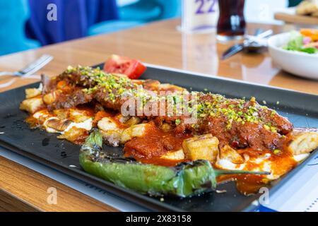 Türkischer Kebab mit Pistazien, serviert mit aufgeschnittenem Fladenbrot, Joghurt und Tomatensauce. Stockfoto