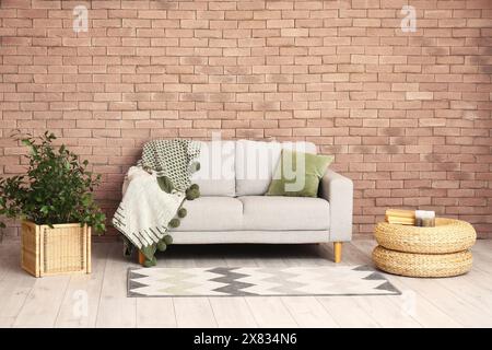 Das Innere des modernen Wohnzimmers mit grauem Sofa in der Nähe der Backsteinmauer Stockfoto